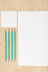 Blanks of empty paper with pencils on a wooden surface.