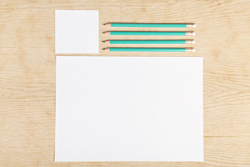 Blanks of empty paper with pencils on a wooden surface.