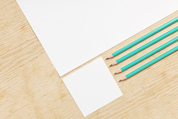 Blanks of empty paper with pencils on a wooden surface.