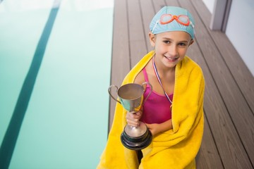 Cute little girl sitting poolside wrapped in towel