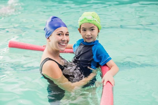 Cute little boy learning to swim with coach