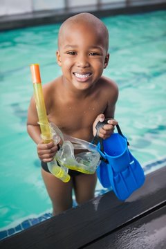 Little boy holding flippers by the pool