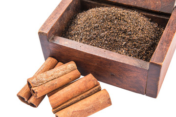 Dried, processed tea leaves in wooden box with cinnamon stick