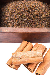 Dried, processed tea leaves in wooden box with cinnamon stick