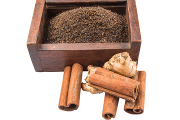 Processed tea leaves in wooden box with ginger and cinnamon