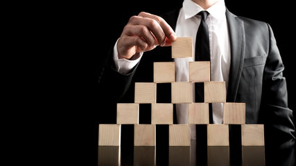 Businessman Arranging Wooden Blocks to Pyramid