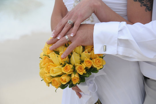 Wedding couple hands on yellow flowers