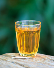 Yellow golden alcoholic drink in a brandy glass, on a wood table