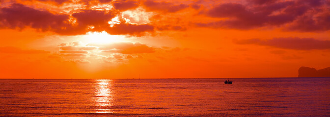 silhouette de bateau dans un coucher de soleil orange