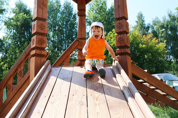 smiling toddler boy sliding on playground