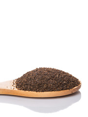 Dried, processed tea leaves in wooden spoon over white 