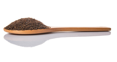 Dried, processed tea leaves in wooden spoon over white 