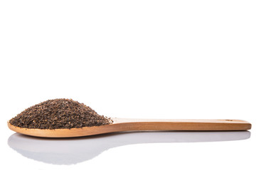 Dried, processed tea leaves in wooden spoon over white 