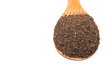 Dried, processed tea leaves in wooden spoon over white 