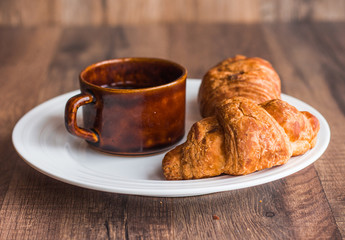 croissant with chocolate on a white plate, a cup of coffee