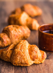 croissant with chocolate on a wooden board, coffee cup