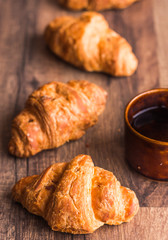 croissant with chocolate on a wooden board, coffee cup