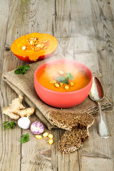 Pumpkin soup in bowl on vintage wooden background