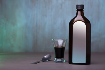Bottle, spoon and glass with syrup