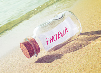 Bottle with a message Phobia on beach. Fear concept