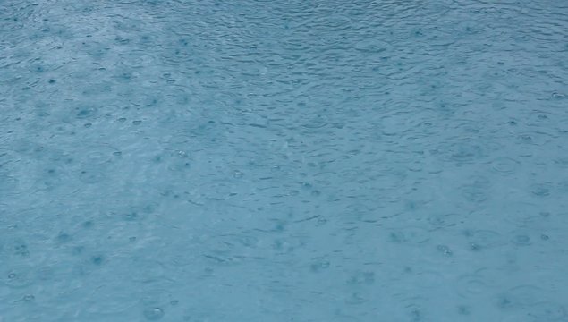 Regentropfen fallen in Swimmingpool  im Urlaub