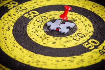 Red pin stuck to a man shape jigsaw puzzle piece on old target