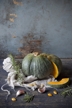 pumpkin cut in half on table with rosemary and garlic