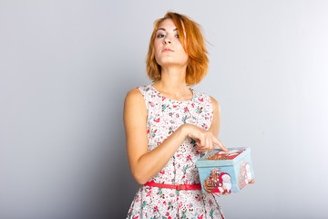 Beautiful red-haired girl with gift box in hands