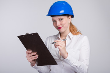 Junge Ingeneurin mit Schutzhelm und Klemmbrett