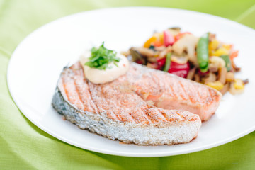 Grilled Salmon with Fresh vegetables on green background