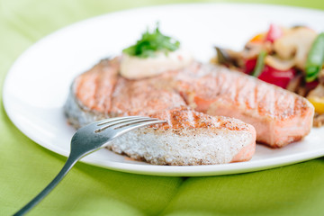 Grilled Salmon with Fresh vegetables on green background