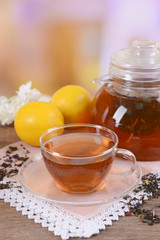 Teapot and cup of tea on table on light background
