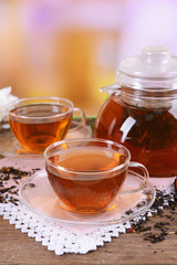 Teapot and cups of tea on table on light background