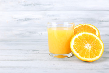 glass of juice with fresh orange on grey wooden table