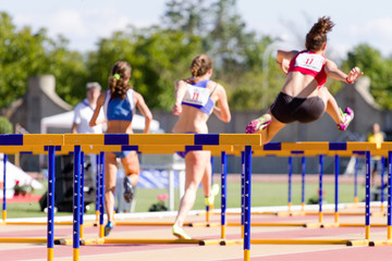 Obraz premium Runner jumping hurdles on track