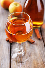 Apple cider in wine glass and bottle, with cinnamon sticks and