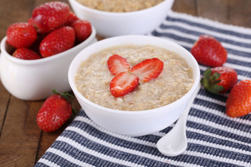Tasty oatmeal with strawberry on table close-up