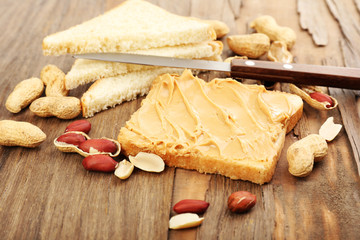 Slice of bread with creamy peanut butter, on wooden table