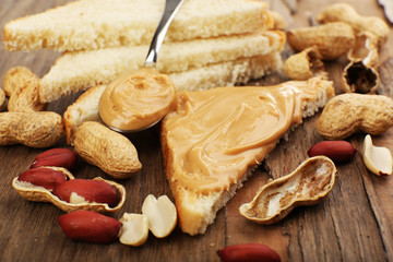 Fototapeta na wymiar Slice of bread with creamy peanut butter, on wooden table