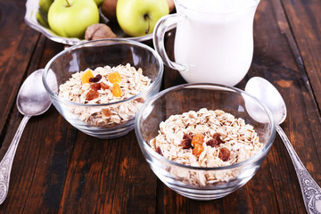 Oatmeal in bowls, yogurt, apples, dried apricots and walnuts