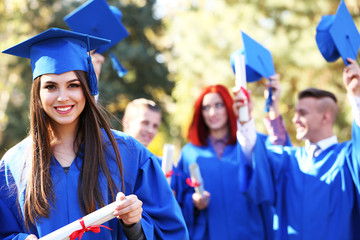 Graduate students wearing graduation hat and gown, outdoors