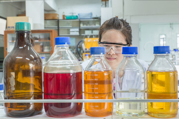 Close up of beautiful asian scientist looking at chemical bottle
