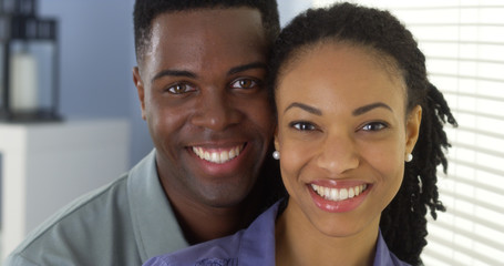 Portrait of young black couple holding each other looking at camera