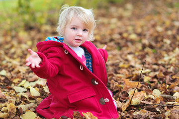 Little girl playing in autumn park