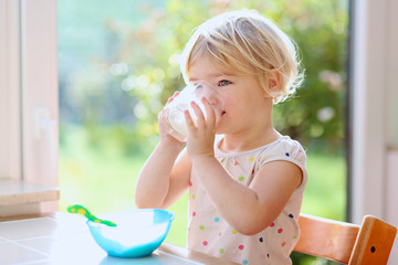 Little girl having healthy breakfast in kitchen