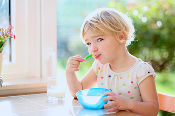 Little girl having healthy breakfast in kitchen