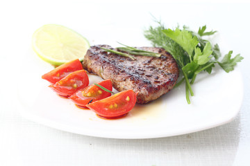 serving of meat with vegetables on a plate of white background