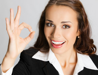 Businesswoman with okay gesture, over grey