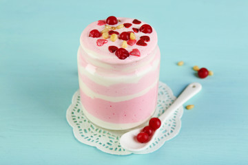 Cranberry milk dessert in glass jar, on color wooden background