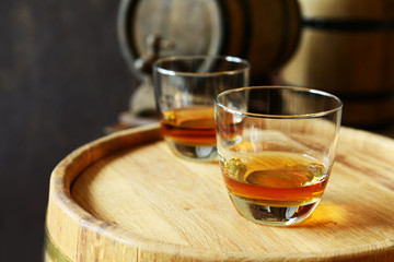 Glasses of brandy in cellar with old barrels